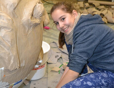 Eine Jugendbotschafterin mit langen braunen Haaren arbeitet an einer ihrer Figuren. Sie trägt ein blaues Oberteil und eine Hose. 