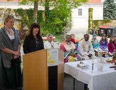 Eine Frau spricht ins Mikrofon, die anderen hören ihr aufmerksam zu.