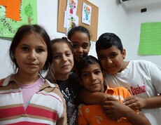 Fünf Kinder im Kinderzentrum Eden in Tirana, die fröhlich und eng beieinander stehen und in die Kamera schauen.