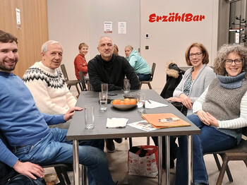 Fünf Personen sitzen in einem Neubau an einem Tisch und schauen in die Kamera.