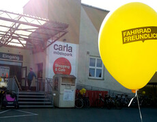 Ein gelber Luftballon befindet sich im Vorder- und im Hintergrund ein großes Betriebsgebäude.