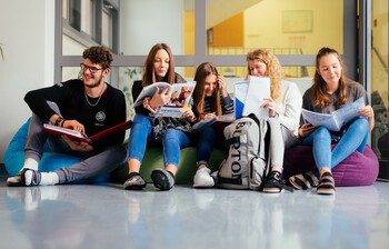 Ein Schüler und fünf Schüler*innen sitzen auf Sitzsäcken im Gand der Schule und lernen miteinander.