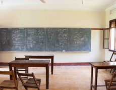 Leerer Klassenraum mit langer Kreidetafel voller Mathematikaufgaben, einfachen Holzschulbänken und einem Fenster – Unterrichtsraum des Caritas-Projekts Teaching Teachers im Südsudan.
