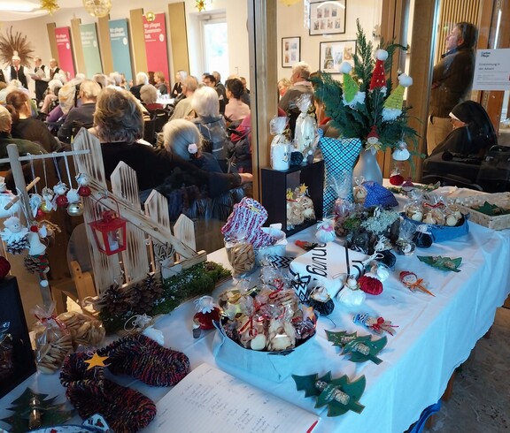 Tisch mit handgefertigten Weihnachtsartikeln, Besucher*innen im Hintergrund