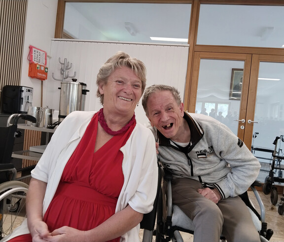 Zwei Bewohner*innen sitzen nebeneinander bei Kaffee im Gemeinschaftsraum und nehmen an der Muttertagsfeier teil.