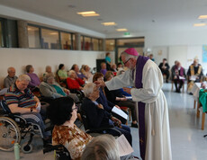 Bischof Josef Marketz teilt das Aschenkreuz an sitzende Bewohner*innen im Saal des Haus Martha aus.