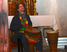 In der Pfarrkirche von Frastanz spielt ein Afrikaner Trommel. Er ist komplett in Schwarz gekleidet. 