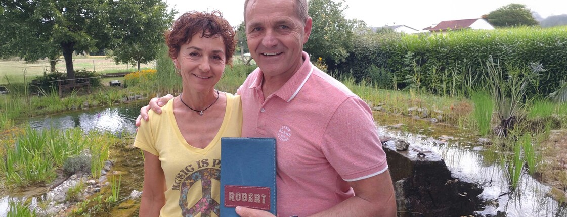 Eine Frau und ein Mann stehen zusammen und der Mann hält ein Büchlein in der Hand.