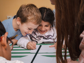 Zwei Kinder haben Spaß daran, etwas in ein Heft zu schreiben.