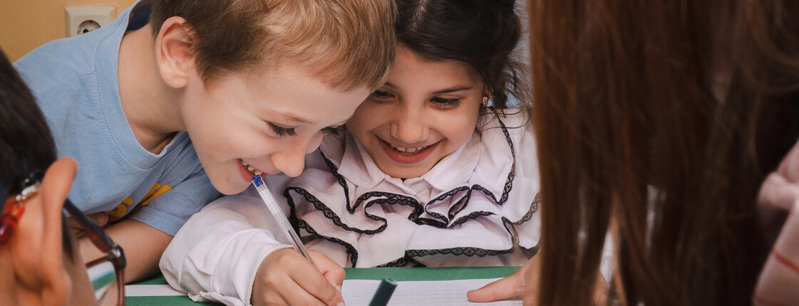 Zwei Kinder haben Spaß daran, etwas in ein Heft zu schreiben.