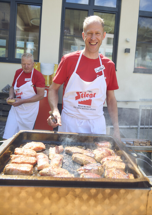Ein Mann steht an einem Griller und grillt Fleisch