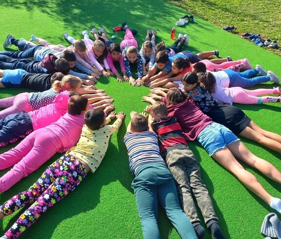Kinder liegen im Gras im Kreis