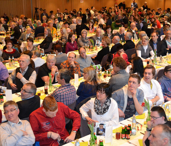 Typisches Bild einer Festgemeindschaft. Lange Tische und viele Menschen. 