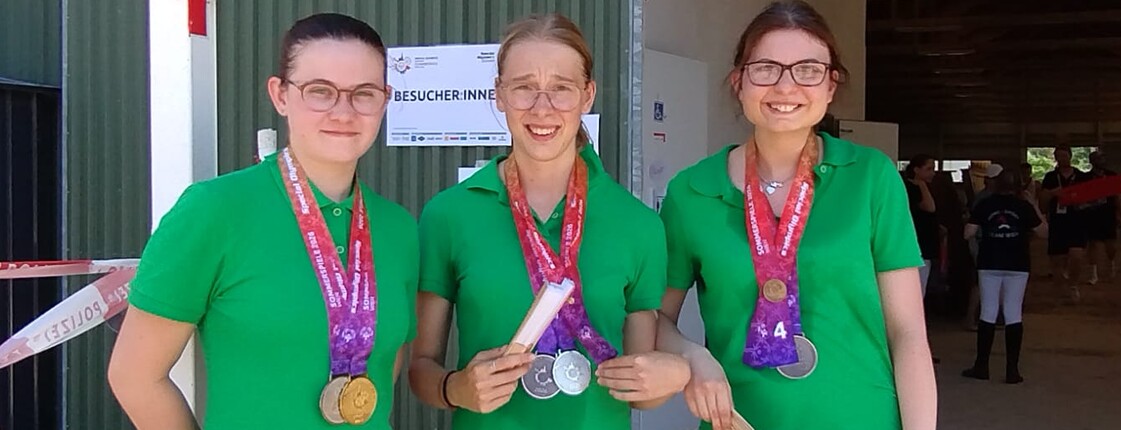 Szenerie: Drei junge Frauen mit ihren bei Reitbewerben gewonnenen Medaillen
