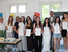 Gruppe von Schüler*innen und Lehrpersonen mit Zertifikaten bei Peer‑Mediation-Auszeichnung im Klassenraum