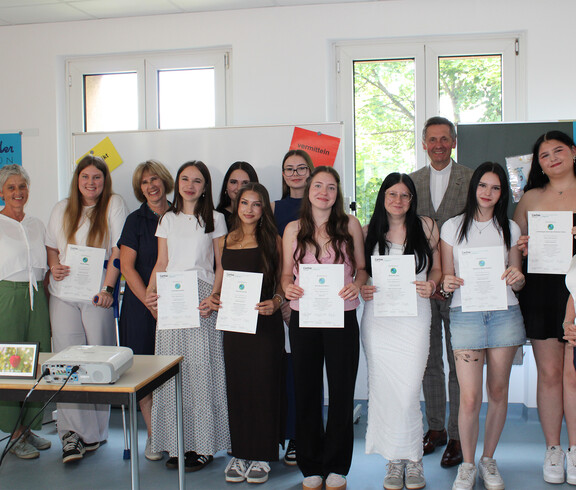 Gruppe von Schüler*innen und Lehrpersonen mit Zertifikaten bei Peer‑Mediation-Auszeichnung im Klassenraum