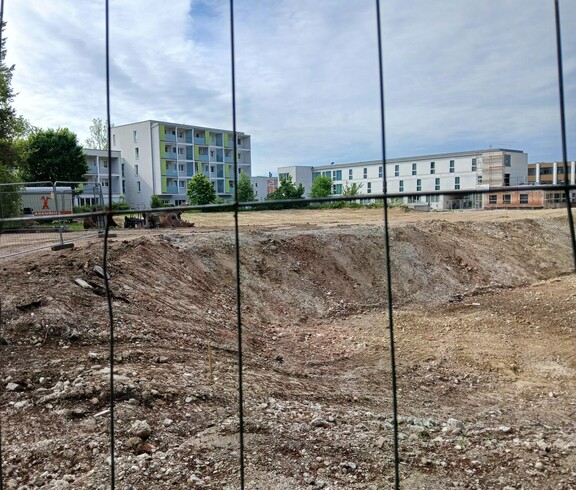 Blick durch ein Baustellengitter auf deine Bebauungsfläche
