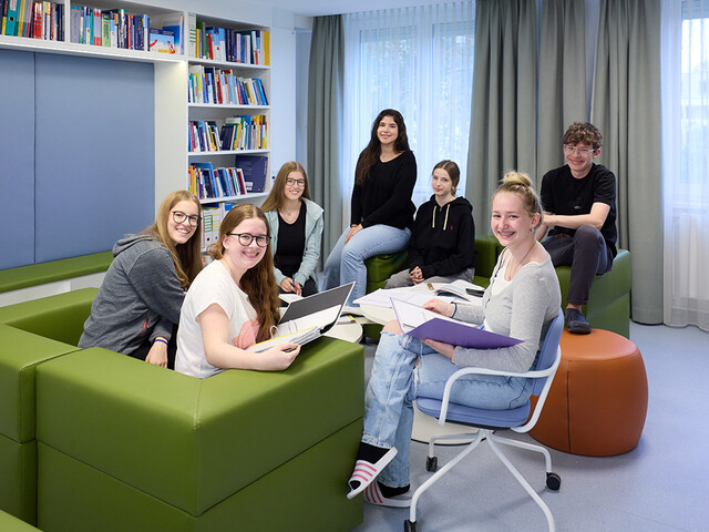 Kinder sitzen in einer Bibliothek, lernen und lachen