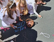 Mehrere Kinder verzieren bei einem Besuch im Pflegewohnhaus den Boden mit bunter Kreide und Blüten, um den Bewohnerinnen und Bewohnern eine Freude zu bereiten.