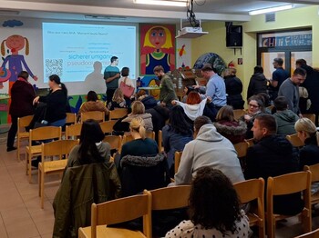 Vortragssituation in einem Klassenzimmer, im Publikum viele Eltern, vor einem Beamerbild der Vortragende