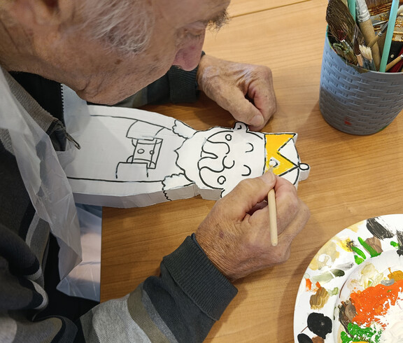 Nahaufnahme einer Hand, die eine Holzfigur der Heiligen Drei Könige bemalt
