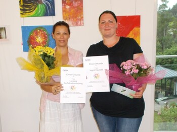 Zwei geehrte Tagesmütter mit Urkunden und Blumensträußen