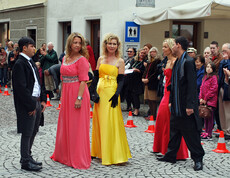 Frauen und Männer im mittleren Alter sind auch bei der carla Modeschau beim Reuse Day in der feldkircher Innenstadt dabei. Die Damen tragen ein langes rotes bzw. gelbes Kleid, die Herren einen schwarzen Anzug. 