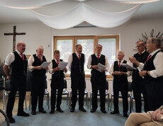 Der Männerchor Lavamünd singt bei der Muttertagsfeier im Gemeinschaftsraum des Hauses Maria vor sitzenden Bewohner*innen.