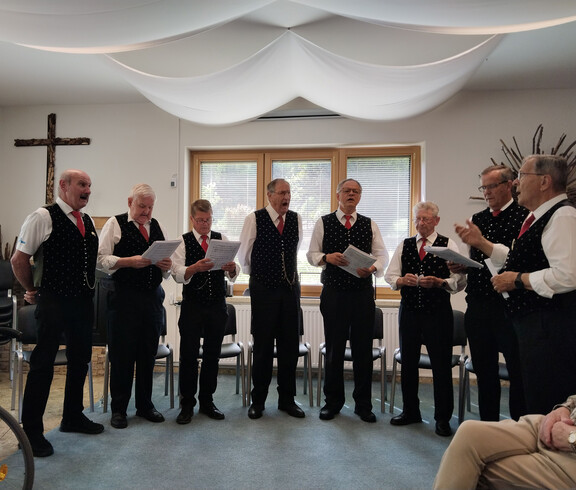 Der Männerchor Lavamünd singt bei der Muttertagsfeier im Gemeinschaftsraum des Hauses Maria vor sitzenden Bewohner*innen.