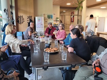 Fünf Personen sitzen in einem Neubau an einem Tisch und schauen in die Kamera.