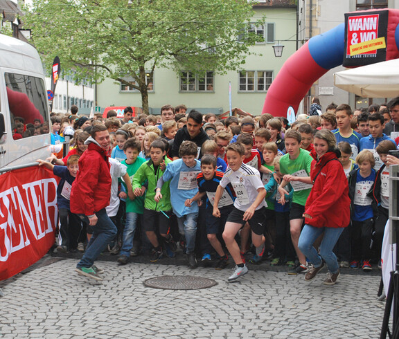 Startschuss bei einem Laufwettbewerb in der feldkircher Innenstadt. Eine große Anzahl von Menschen stehen in den Startlöchern und sind im Begriff loszurennen.