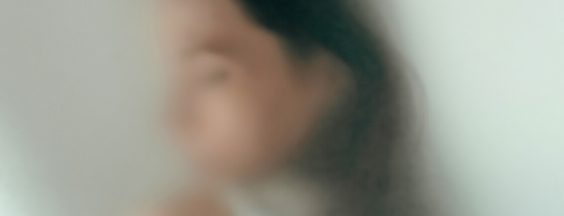Unscharfes Portrait einer Person hinter einer halbtransparenten Oberfläche.